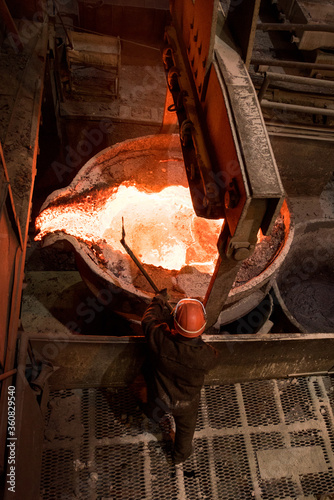 Steelworker at work near the tanks with hot metal photo