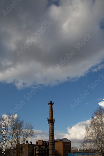 Brick boiler station with a pipe against the blue sky with white clouds