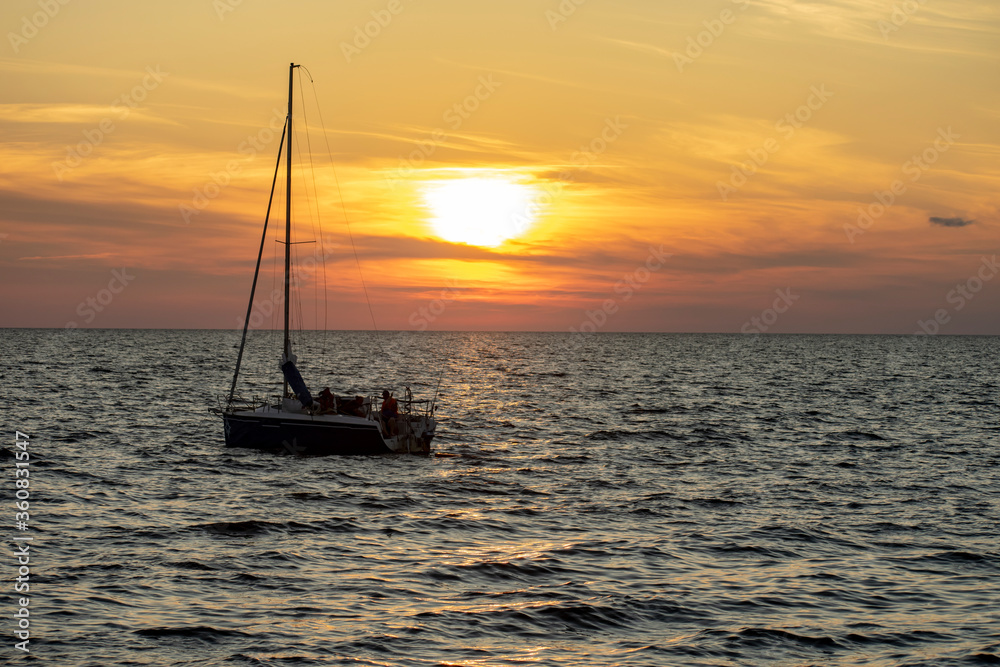 Sailing yacht bobs on the waves at sunset.