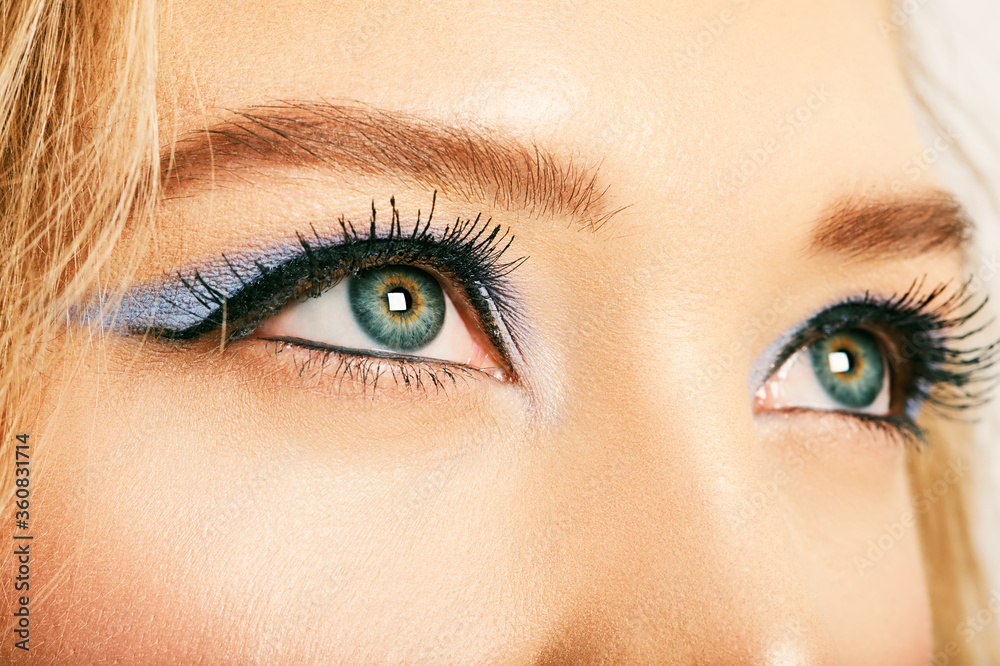 Fototapeta premium Close up image of open female blue eyes with bright makeup