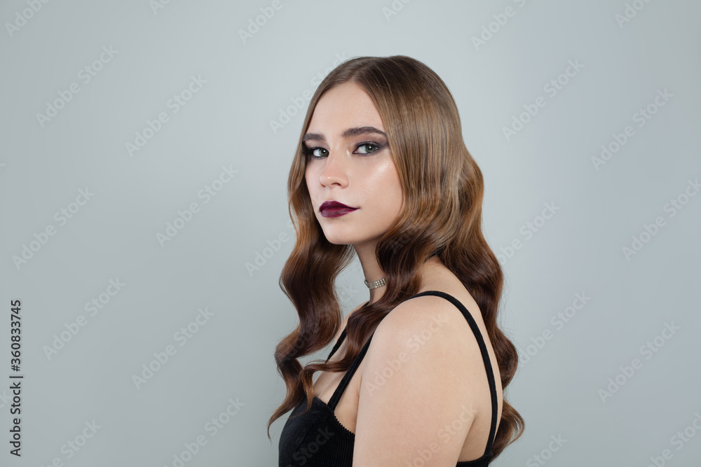 Fototapeta premium Young fashion model woman with brown curly hair and dark lipstick makeup on white