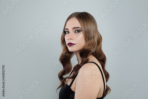 Young fashion model woman with brown curly hair and dark lipstick makeup on white