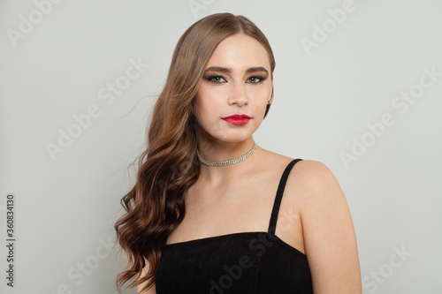 Beautiful young woman with red lips makeup and long brown curly hair portrait