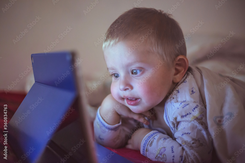 Boy lies in bed and watching tablet Boy lies in bed and watching tablet