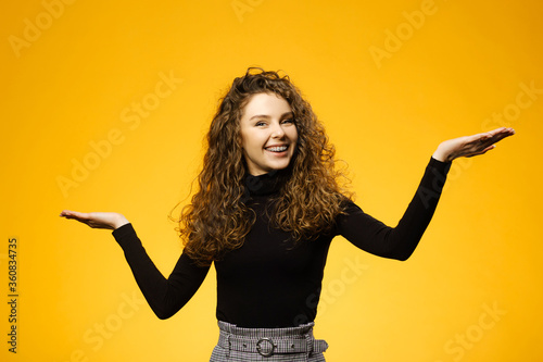 Pretty girl with curly hair on yellow background