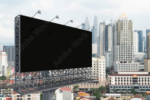 Blank black road billboard with Kuala Lumpur cityscape background at day time. Street advertising poster, mock up, 3D rendering. Side view. The concept of marketing communication.