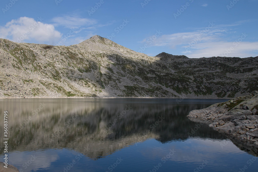 The view of mountain reflection in Lago della Vacca, Lombardy, Italy.