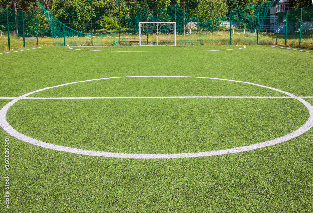 Soccer field with artificial green grass near the school. Amateur football field. Sunny summer day Soccer field with artificial green grass near the school. Amateur football field. Sunny summer day