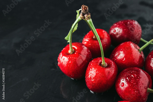 Fresh red cherries with water drops on dark background, close-up view