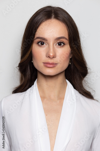 Photobooth portrait of a brunette caucasian woman reaching the standards of an official passport photo.