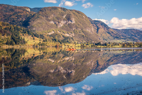 Fototapeta Naklejka Na Ścianę i Meble -  Two people row on Lake Bohinj in Slovenia on a clear autumn day. Reflection of the Alps in water. Water activity