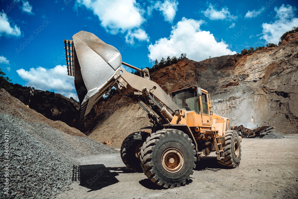 Fototapeta premium Industrial heavy duty wheel loader working on construction site. Industrial machinery loading and transporting gravel