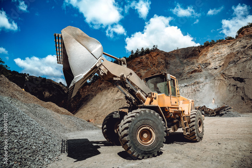Industrial heavy duty wheel loader working on construction site. Industrial machinery loading and transporting gravel