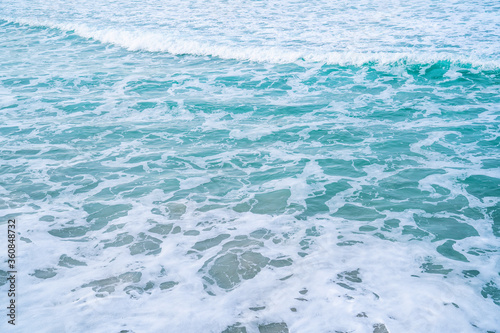 Soft blue ocean wave on sandy beach. Background textured.