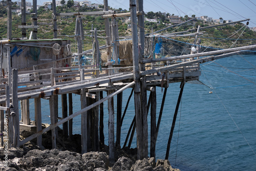Typical traditional fishing trabucco on wooden poles at the beach with rocks near Vieste in Italy. 