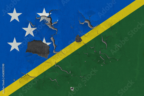 Solomon Islands flag close up old, damaged and dirty on wall peeling off paint to see inside surface. Vintage National Concept.