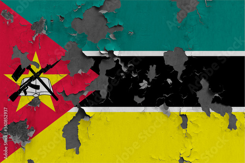 Mozambique flag close up painted, damaged and dirty on wall peeling off paint to see concrete surface. Vintage National Concept.
