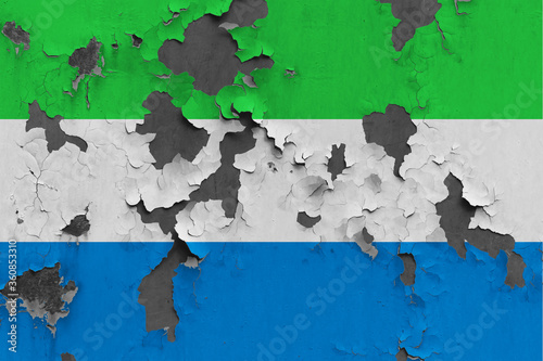 Sierra Leone flag close up painted, damaged and dirty on wall peeling off paint to see concrete surface. Vintage National Concept.