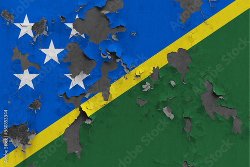 Solomon Islands flag close up painted, damaged and dirty on wall peeling off paint to see concrete surface. Vintage National Concept.