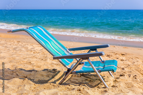 Fototapeta Naklejka Na Ścianę i Meble -  One blue beach chair at coast with sea