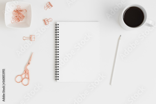 Top view of a white notebook mockup with workspace accessories and a succulent plant on a white table.