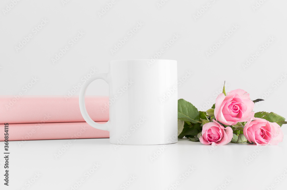 Mug mockup with books and a bouquet of pink roses on a white table. Mug mockup with books and a bouquet of pink roses on a white table.