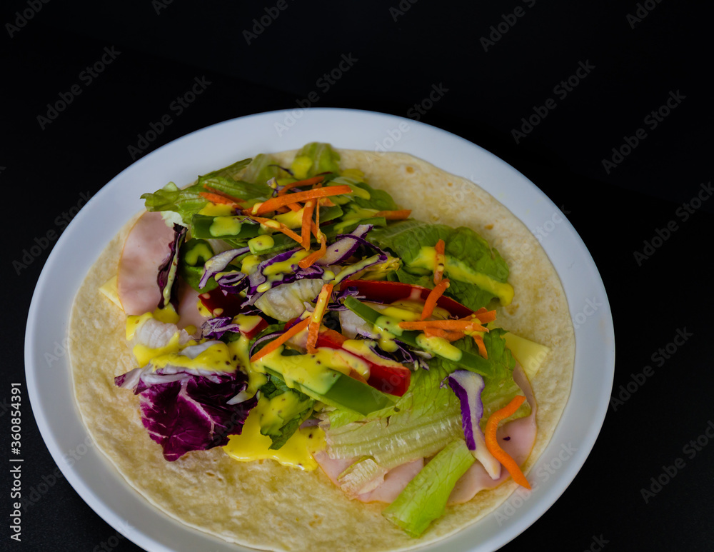 Ham, mozzarella cheese, and vegetables covered with honey mustard on flour tortilla Ham, mozzarella cheese, and vegetables covered with honey mustard on flour tortilla