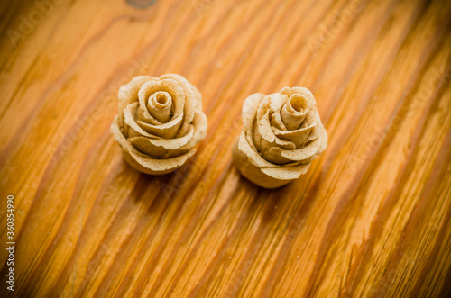 Closeup of beautiful and sweet rose shaped pastry baked to a a light brown on wooden background