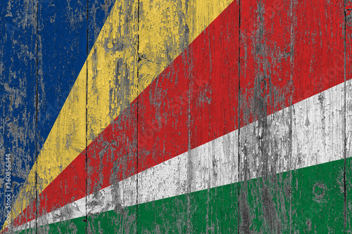 Seychelles flag on grunge scratched wooden surface. National vintage background. Old wooden table scratched flag surface.
