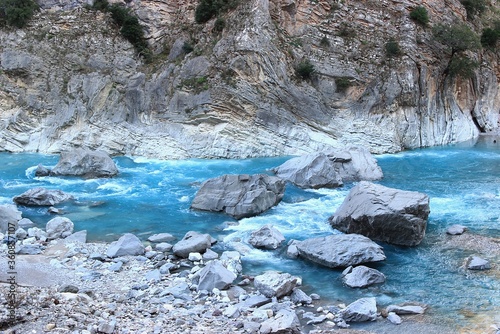 Rushing river with blue water between big rocks into a gorge