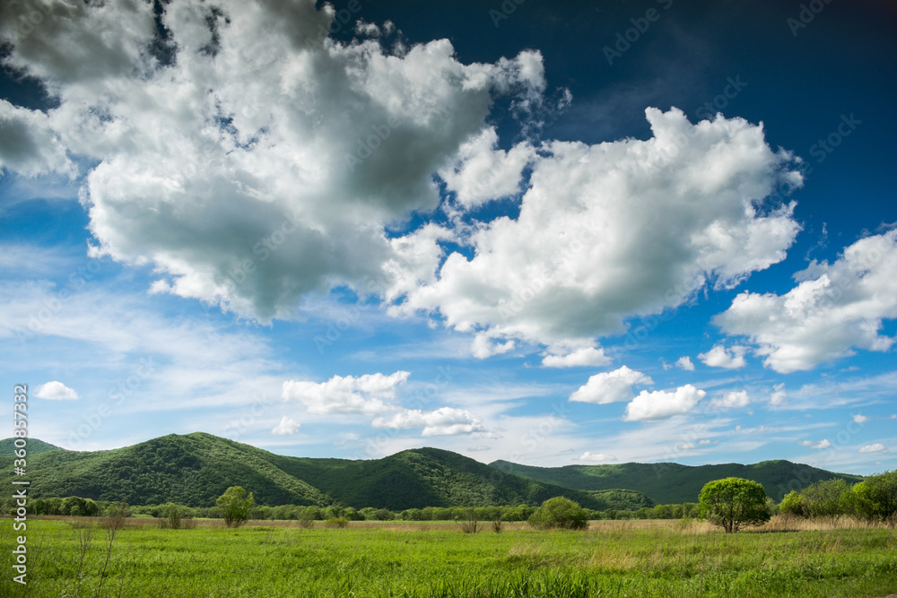 Summer landscape with green meadows and hills, and a blue sky with clouds Summer landscape with green meadows and hills, and a blue sky with clouds