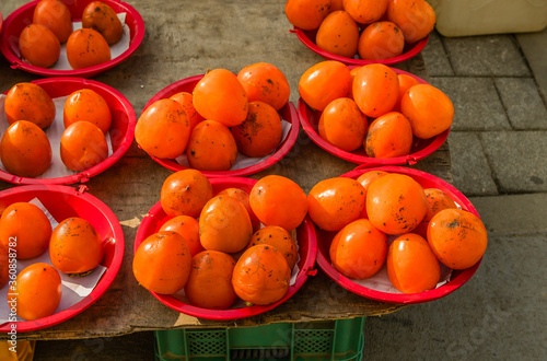 Persimmons in red plastic bowls
