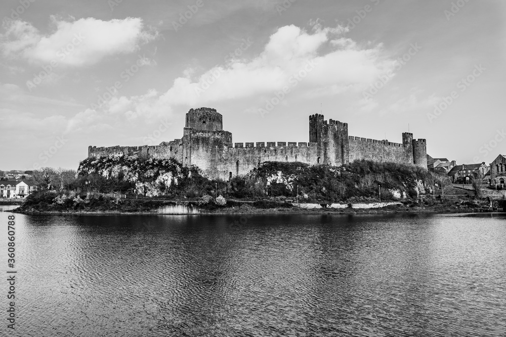 Fototapeta premium Landscape with the ruins of Pembroke Castle on the shores of river Pembroke, the original family seat of the Earldom of Pembroke in Pembrokeshire, Wales, UK