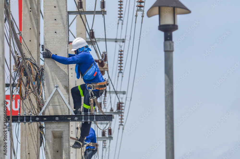 Electricians are climbing on electric poles to install and repair power lines.