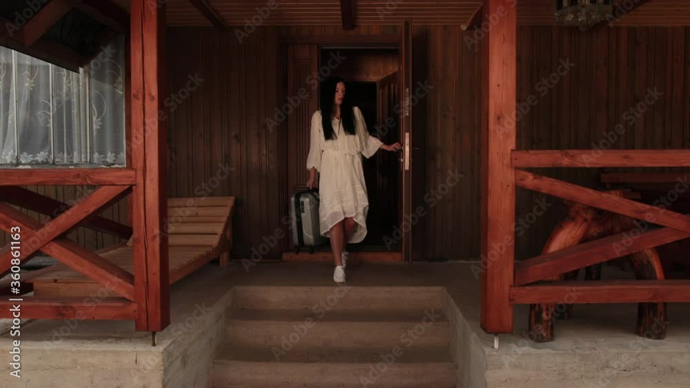 Rear view of a beautiful slim young brunette woman with suitcase leaves hotel room after long therapeutic vacation. Female goes on business trip leaving house, luggage, tourism, departure, fees travel Rear view of a beautiful slim young brunette woman with suitcase leaves hotel room after long therapeutic vacation. Female goes on business trip leaving house, luggage, tourism, departure, fees travel