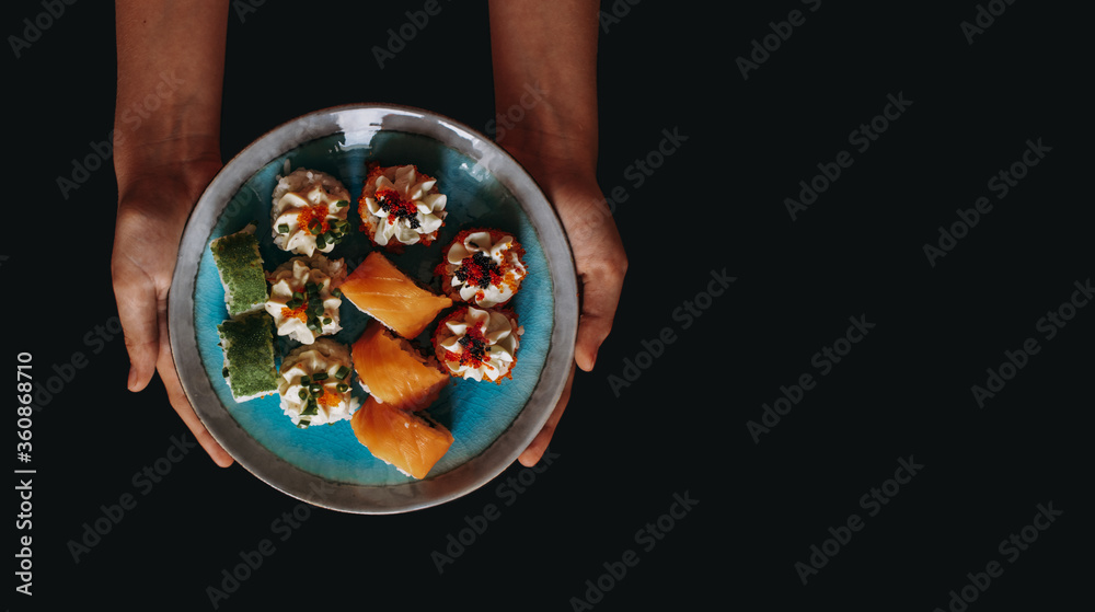 Sushi and rolls in a beautiful plate on a black background