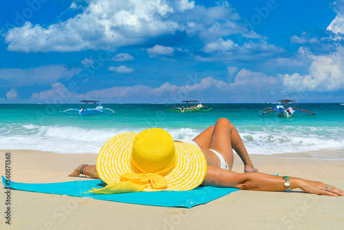Woman in yellow bikini lying on tropical beach
