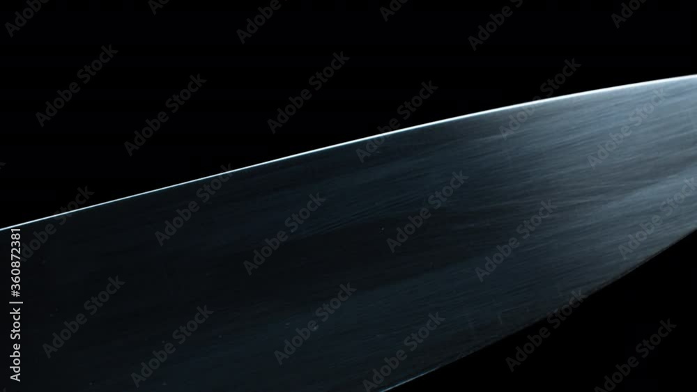 Extreme close up of three professional chef knives on black background. Macro shooting, motion control system. Smooth camera movement, top view