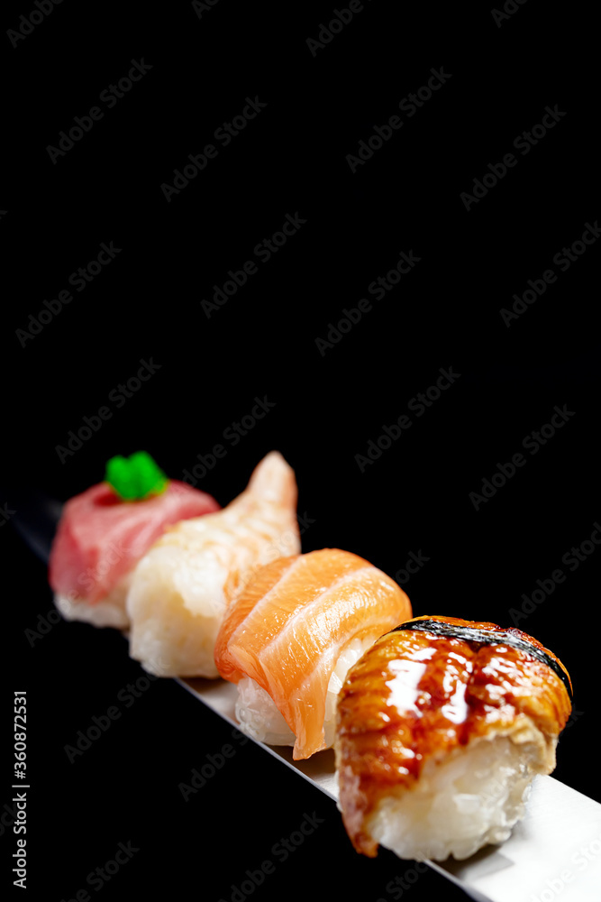 Japanese rolls and seafood sushi on a katana sword on a black background Japanese rolls and seafood sushi on a katana sword on a black background