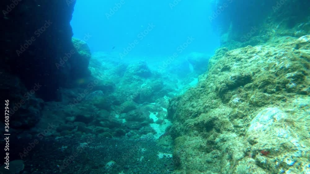 Underwater view in blue ocean with rocks and stones Underwater view in blue ocean with rocks and stones
