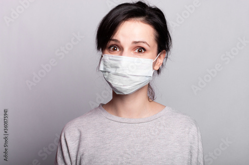 woman in medical mask, closeup portrait, gray studio background
