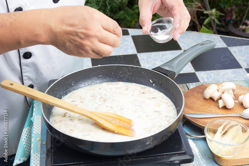 Chef putting salt in the pan for cooking mushroom cream soup