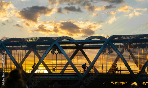 Fotografía Cylists cross the bridge in the evening, sunset time , Arganzuela Footbridge, Pu