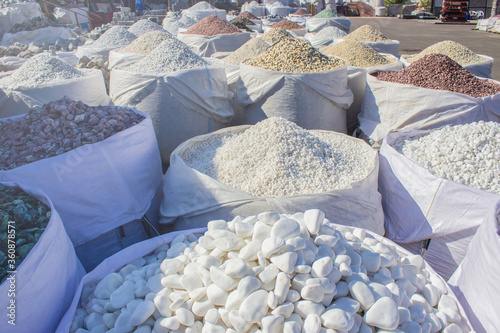 decorative river stones in a big bag outside on the street in factory or decorative stone shop for garden and building, close up macro, copy space for text. Landscaping construction concept