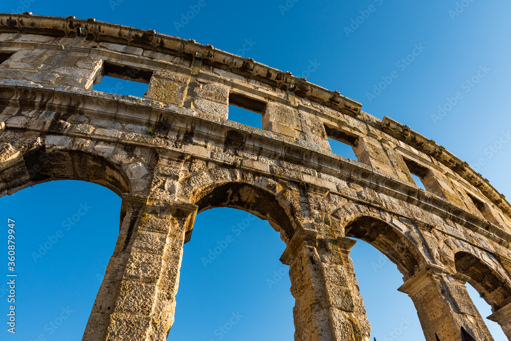 Ancient Roman amphitheater with blue sky on the background