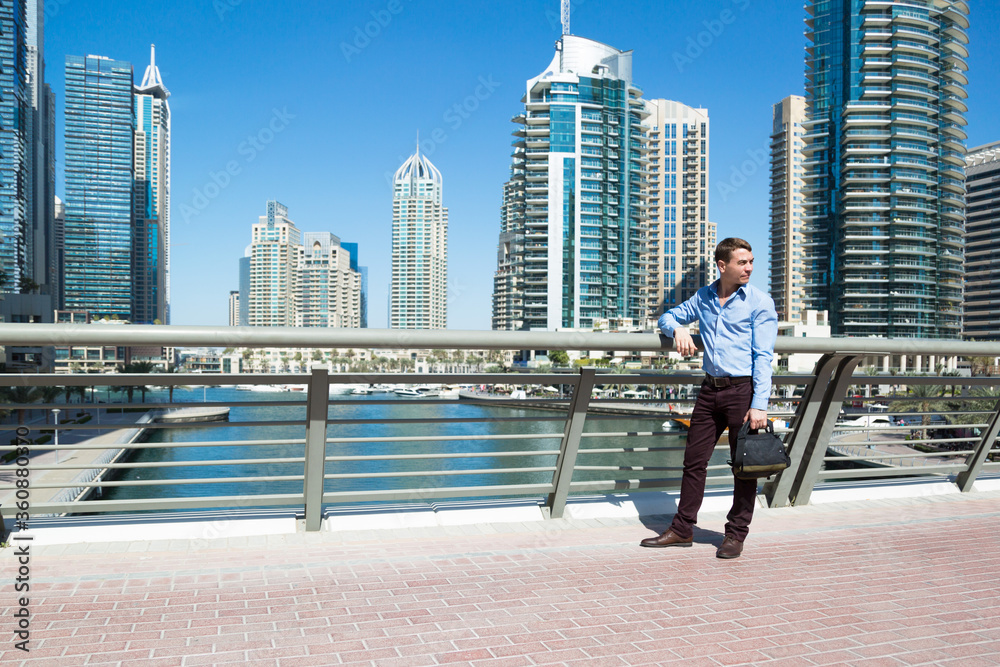 European tourist looks at the views of Dubai. A tourist stands on a bridge over water canal in Dubai. European tourist looks at the views of Dubai. A tourist stands on a bridge over water canal in Dubai.