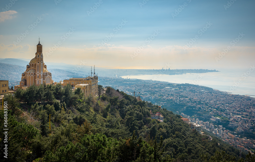 Our Lady of Lebanon Maronite church sits on a hill over the Jounieh bay, with Beirut capital city in the background, in Lebanon, Middle East