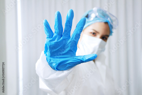 Asian Scientific experimenter Woman Wearing blue protective rubber gloves and showing stop hand sign for Covid-19 virus pathogens and inhibit the spread of germs. photo