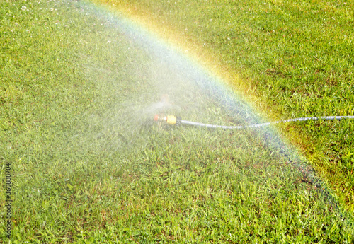 Lawn water sprinkler spraying water over lawn green fresh grass.