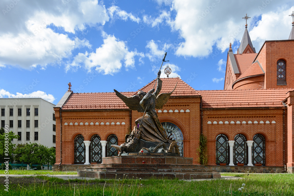 Red Church in Minsk. Catholic church of St. Simeon and St. Helena. Bronze statue of the Archangel Michael piercing the serpent with a spear. Belarus.